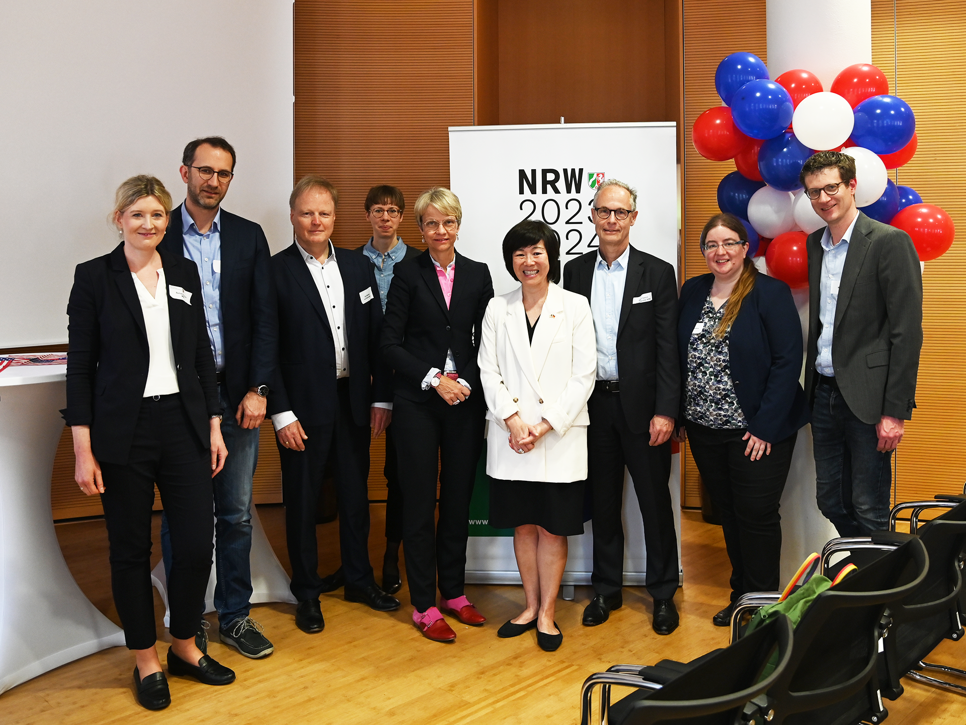 The picture shows a group of people in front of the NRW-USA Year logo.